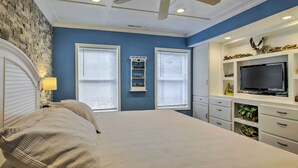 Ein Schlafzimmer mit einem Bett, einem Deckenventilator, einem Fernseher und integrierten Regalen mit Dekoration.