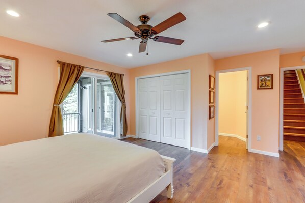 A bedroom with a bed, ceiling fan, and a door leading to a balcony.