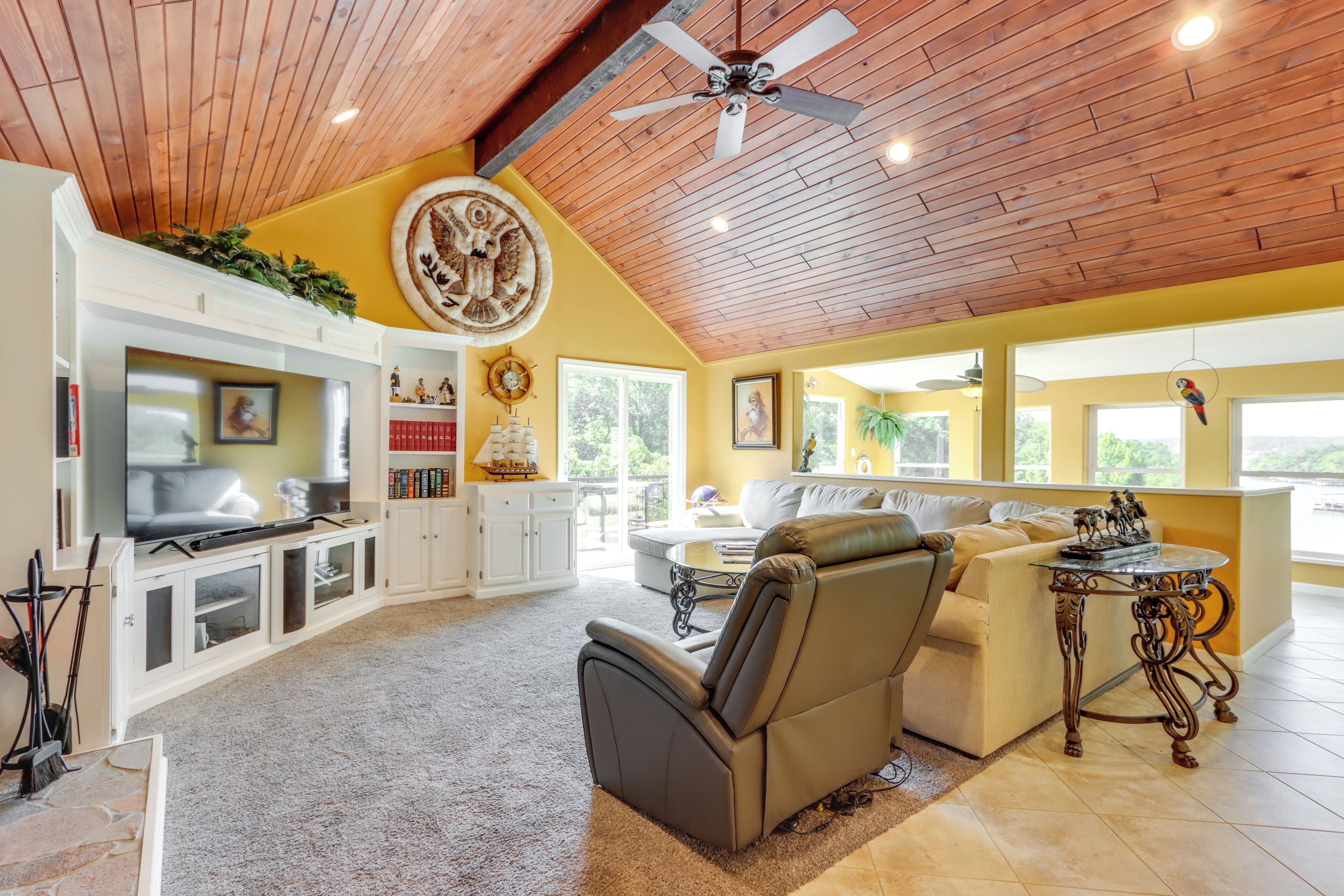 A spacious living area with a high ceiling, a fireplace, a television, and a comfortable seating arrangement.