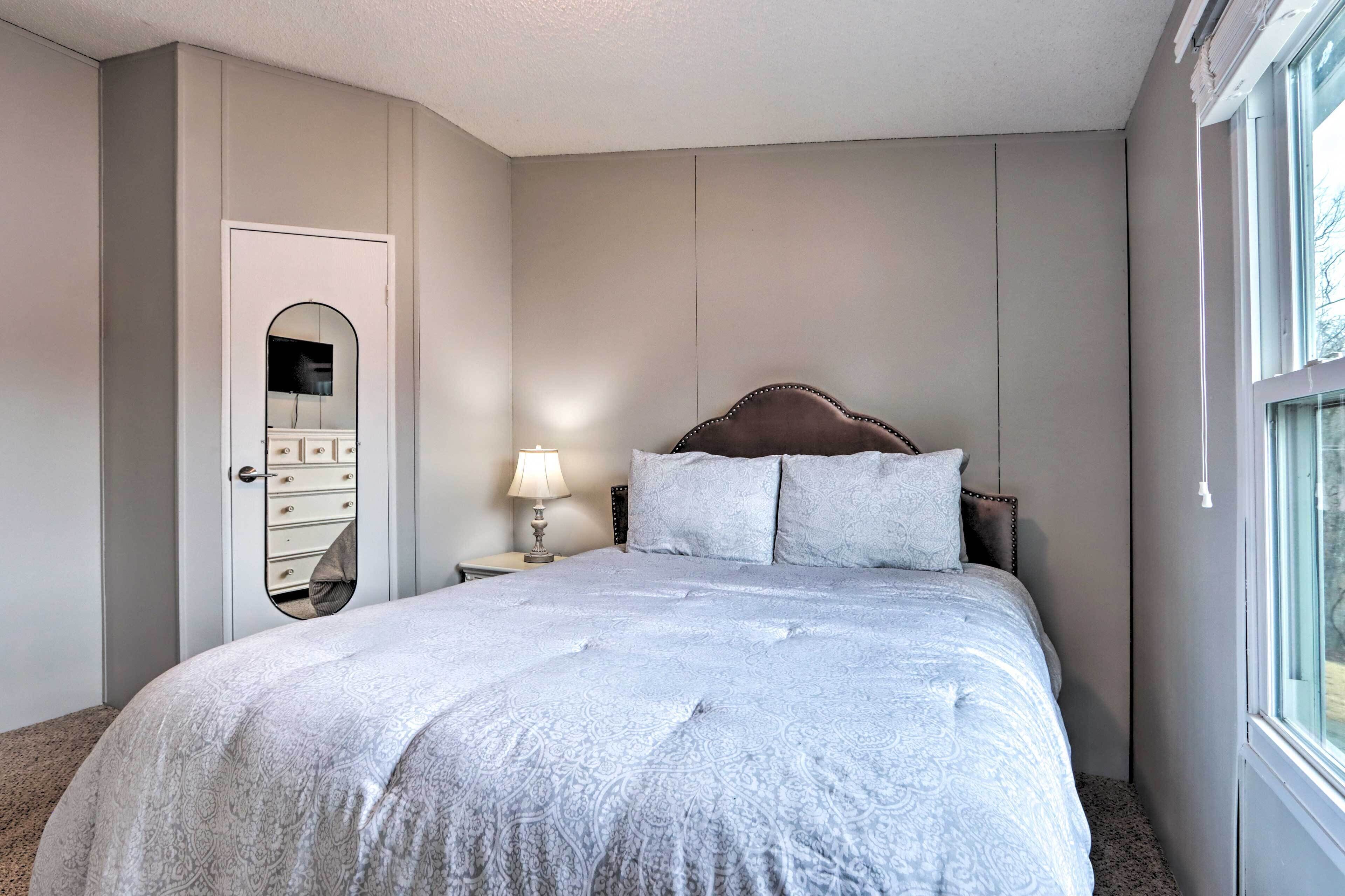A bedroom with a large bed, a nightstand with a lamp, a wardrobe, and a mirror.