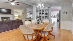 A dining area with a wooden table and chairs, a chandelier, and a kitchen in the background. - 8 Mi to Beach: Lake-view Haven in Linn Creek! (Linn Creek)