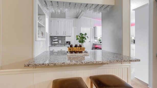 A kitchen with a granite countertop, white cabinets, a welcome sign, and a potted plant. - 8 Mi to Beach: Lake-view Haven in Linn Creek! (Linn Creek)