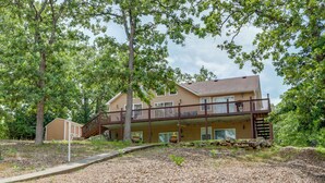 A two-story building with a balcony, surrounded by trees and a gravel path. - 'lazy RS Lakehouse' w/ Hot Tub & Dock in Warsaw! (Warsaw)