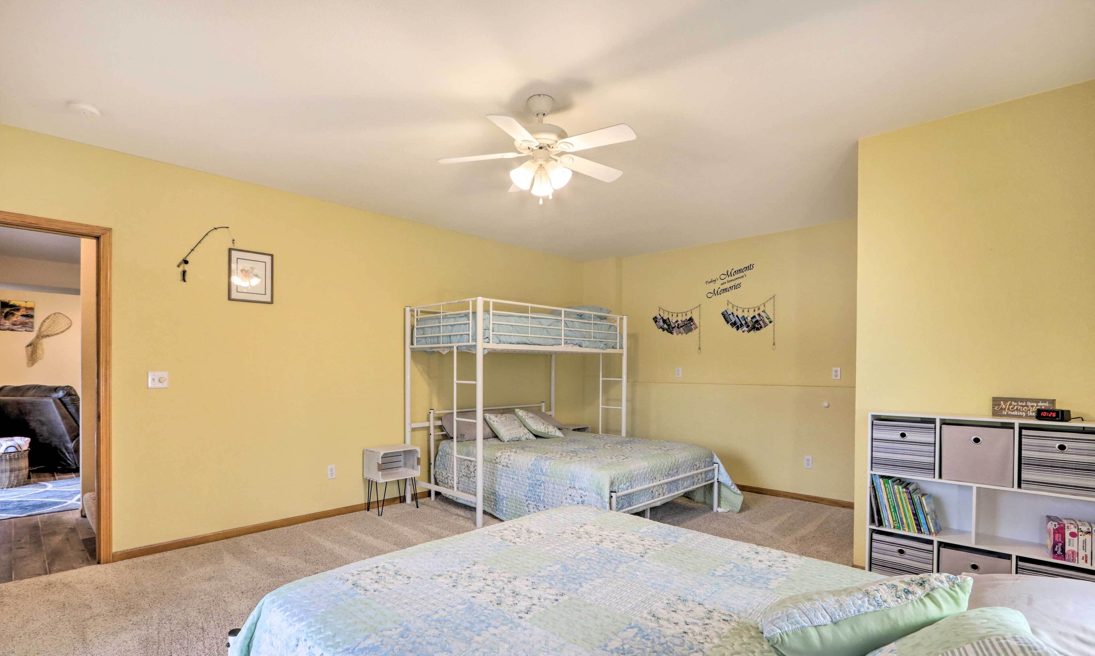 A bedroom with a bunk bed, a ceiling fan, a bookshelf, and a wall with a photo collage.