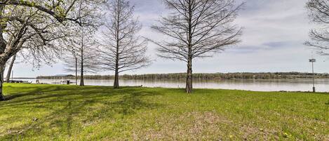 A grassy area with trees and a lake in the background.