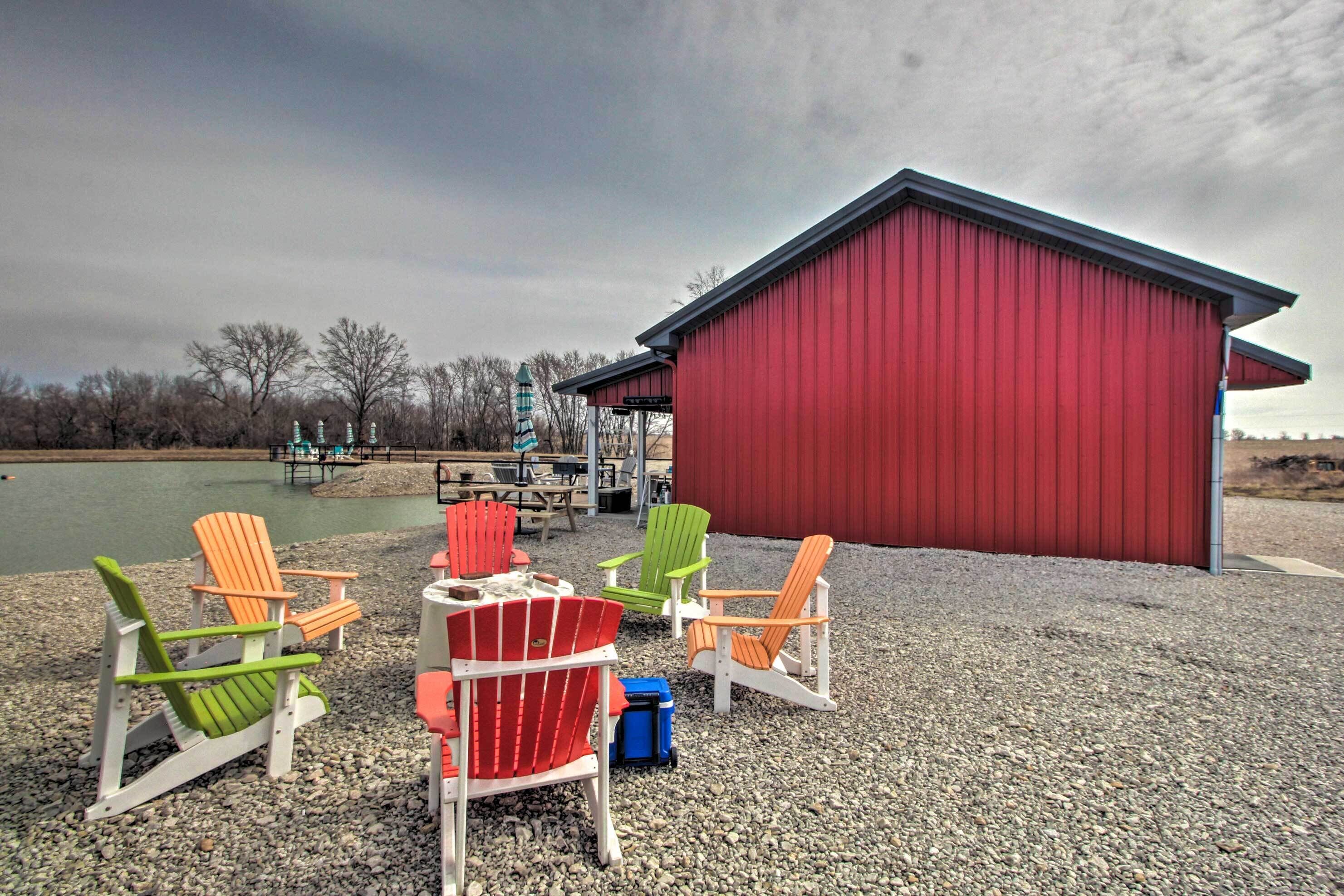 A red building with a gravel ground, surrounded by colorful Adirondack chairs.