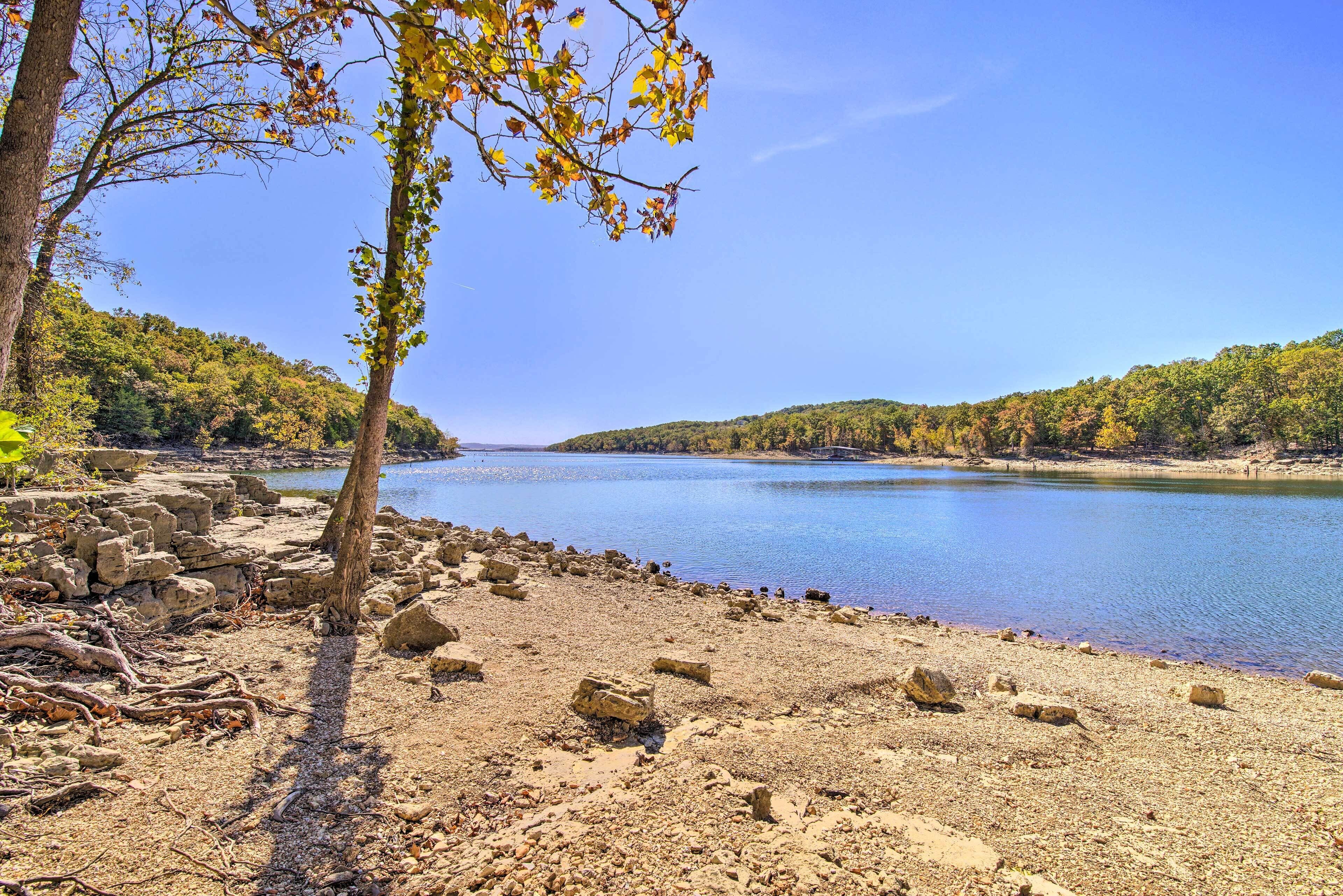 A natural landscape with a lake, rocky shore, and trees.