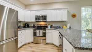 A modern kitchen with white cabinets, stainless steel appliances, granite countertops, and a built-in oven.
