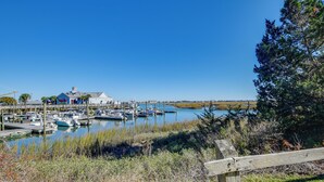 A marina with boats docked, a building with a blue roof, and a grassy area with a wooden fence.