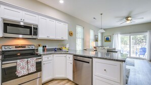 A modern kitchen with white cabinetry, stainless steel appliances, and a granite countertop.