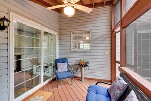 A covered porch with a ceiling fan, a blue chair with a patterned cushion, a wooden table, and a potted plant. - Modern Home w/ Yard + Deck, 1 Mi to Clemson U! (Clemson)