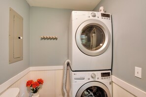 A laundry room with stacked washer and dryer, a wall-mounted electrical panel, and a vase with flowers. - Modern Home w/ Yard + Deck, 1 Mi to Clemson U! (Clemson)
