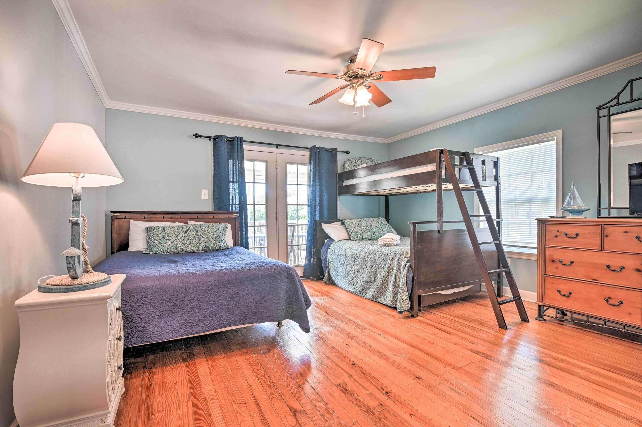 A bedroom with a bunk bed, a dresser, a lamp, and a ceiling fan.