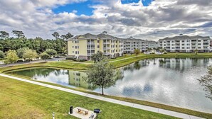 A residential area with a pond, a walking path, and multi-story buildings with balconies. - Magnolia Pointe Condo With Community Pool & More! (Myrtle Beach)