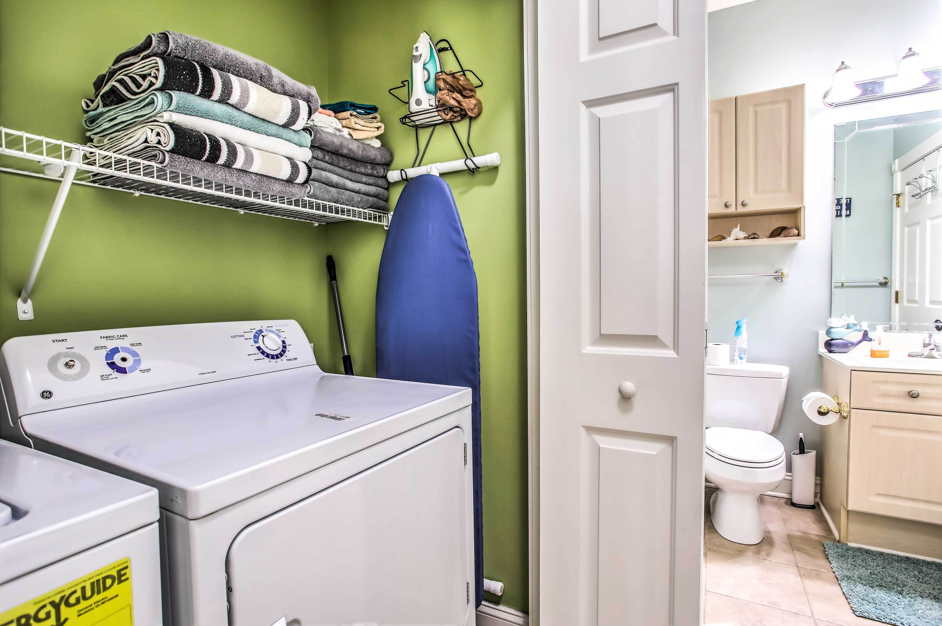 A laundry area with a washing machine, dryer, and iron.