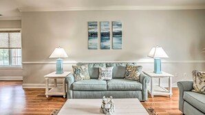 A living room with a grey sofa, two side tables with lamps, a coffee table with a decorative item, and three abstract wall art pieces. - Magnolia Pointe Condo With Community Pool & More! (Myrtle Beach)