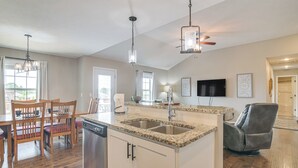 Una cocina amplia con encimeras de granito, lavavajillas y un comedor con sillas y mesa de madera.