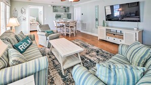 A living room with striped sofas, a coffee table, a TV, and a dining area with chairs and a table. - 1 Mi to Beach + Hot Tub: Murrells Inlet Retreat! (Murrells Inlet)