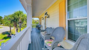 A porch with wicker furniture, a view of the street, and a palm tree. - 1 Mi to Beach + Hot Tub: Murrells Inlet Retreat! (Murrells Inlet)