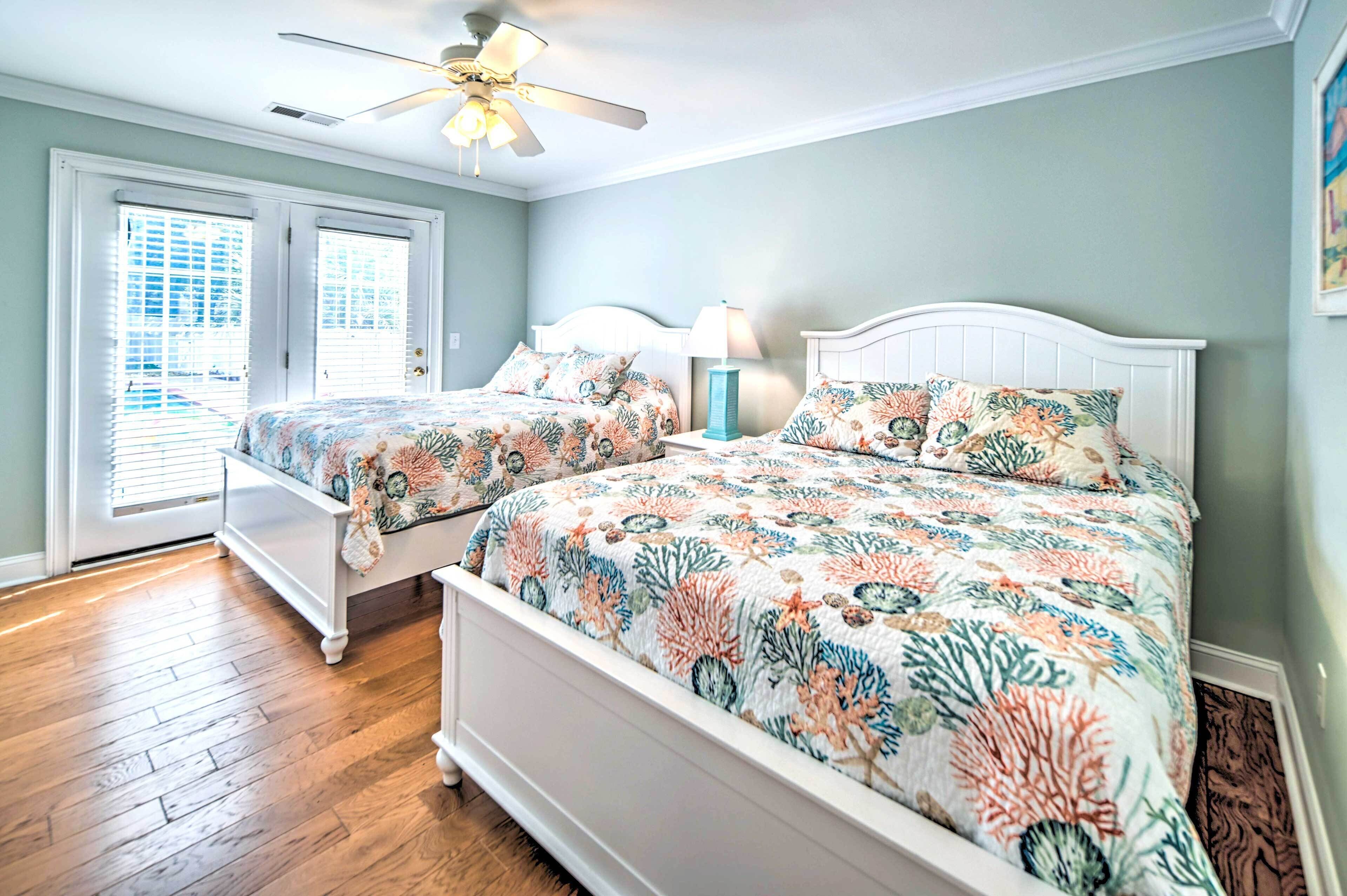 A bedroom with two beds, a ceiling fan, and a window with blinds.