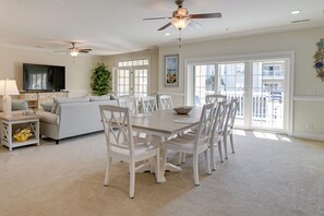 A spacious living room with a dining area, a ceiling fan, a flat-screen TV, and large windows. - Murrells Inlet Golf Resort Condo: 1 Mile to Beach! (Murrells Inlet)