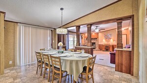 A dining area with a round table set for six, wooden chairs, and a chandelier. - Monett Family Ranch Home w/ Fireplace & Huge Deck! (Purdy)