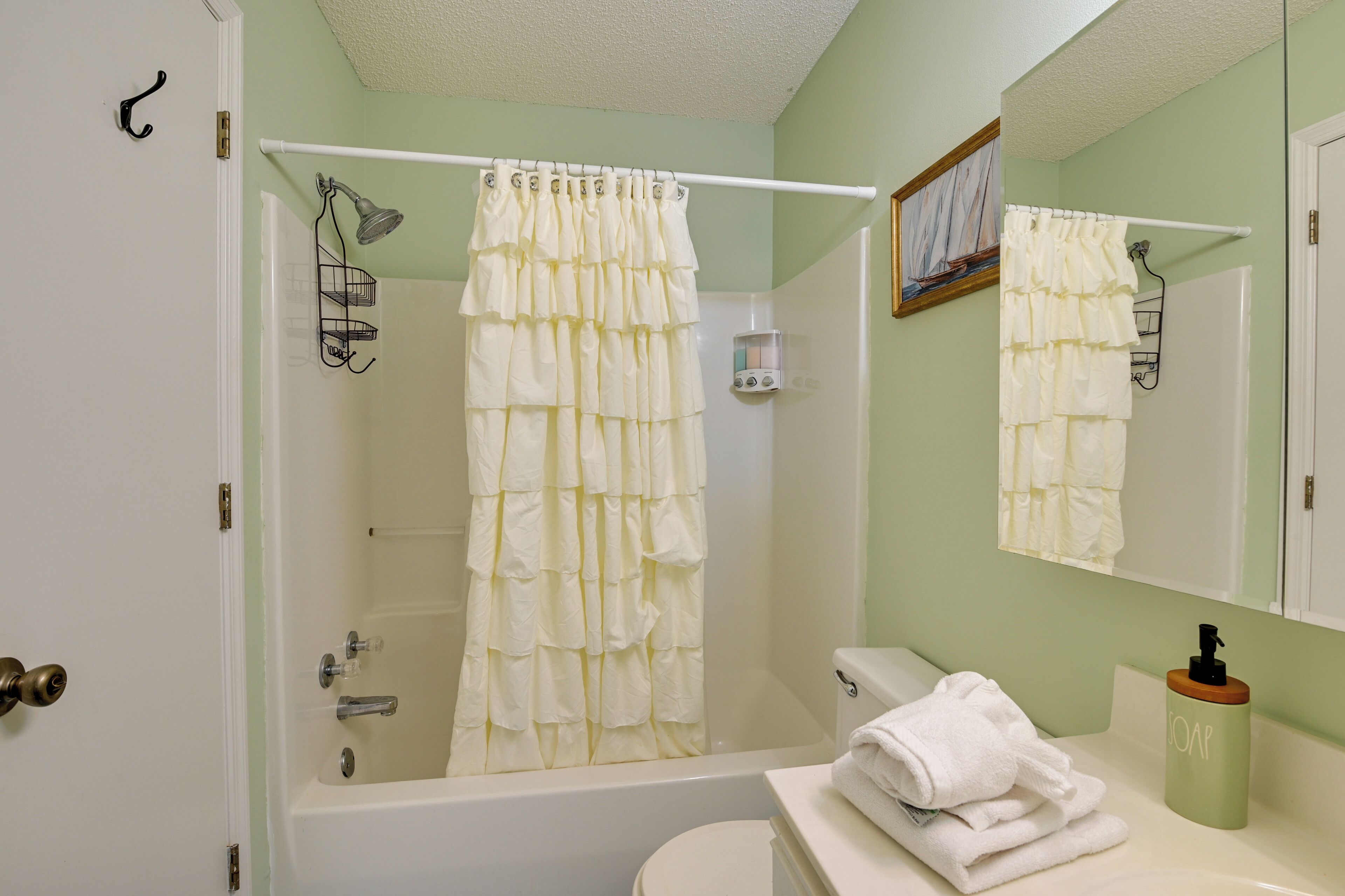 A bathroom with a bathtub, toilet, and a sink with a soap dispenser.