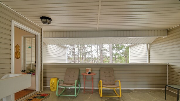 A covered porch with three rocking chairs, a small table, and a window overlooking trees. - Myrtle Beach Condo 2 Mi to Surfside Beach! (Surfside Beach)