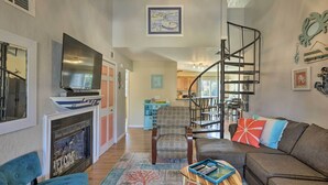 Ein Wohnzimmer mit Kamin, Fernseher, Sofa und Treppe.