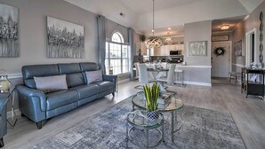 Un salon spacieux avec un canapé en cuir, une table basse en verre et des œuvres d’art accrochées aux murs.