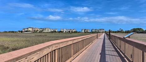 A wooden boardwalk leading to a residential area with buildings in the background.