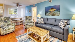 A living room with a grey sofa, two patterned armchairs, a wooden coffee table, and a painting of a sea turtle on the wall. - Walk to Beach: Nautical Hilton Head Resort Condo! (Hilton Head Island)