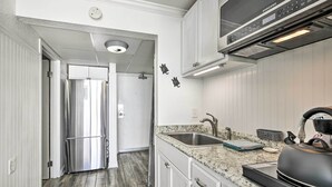 A modern kitchen with white cabinetry, a stainless steel refrigerator, a granite countertop, and a built-in microwave. - Newly Renovated Oceanfront Studio w/ Beach Access (Myrtle Beach)