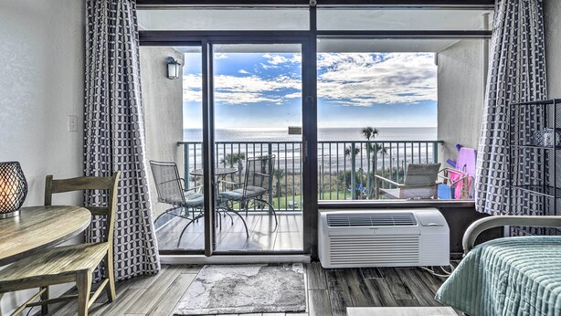 A balcony with a view of the ocean, a table, chairs, and an air conditioning unit. - Newly Renovated Oceanfront Studio w/ Beach Access (Myrtle Beach)