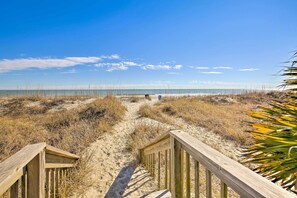 A wooden boardwalk leading to a beach with clear skies. - Walk to Myrtle Beach Boardwalk: Waterfront Condo! (Myrtle Beach)