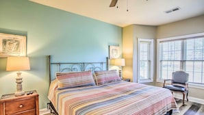 Um quarto com cama, mesas de cabeceira, luminárias e uma cadeira.
