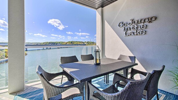 Een balkon met rieten meubels, een tafel en een bord waarop staat 'Naar het Meer'.
