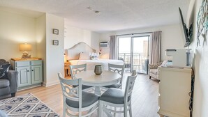 Ett hotellrum med en säng, ett matbord med stolar, en soffa, ett skåp och en tv.