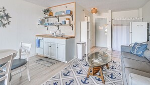 Ett kompakt bostadsutrymme med ett litet kök, en matplats och en sittgrupp med ett soffbord i glas.