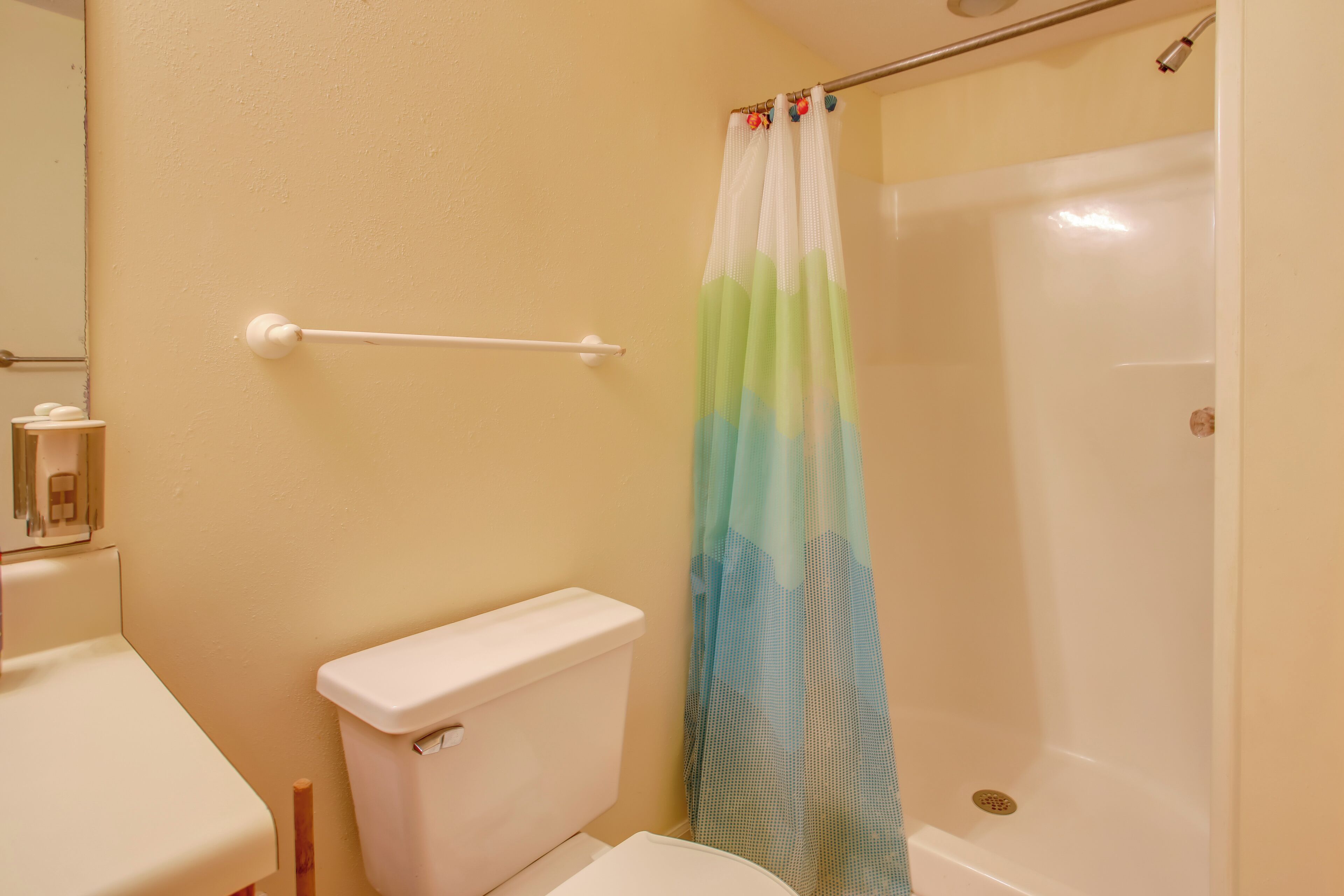 A bathroom with a toilet, a shower curtain, and a bathtub.