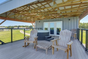 Terraza cubierta al aire libre con sillas y mesa de madera, un jacuzzi y vistas a un campo de golf.