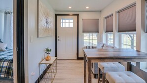 A modern room with a wooden dining table, a bench, a door, and a window with blinds. - One-of-a-kind Container Home on Mount Vernon Farm! (Mount Vernon)