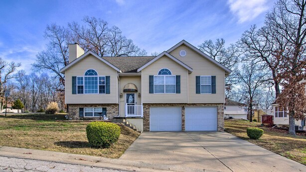 A two-story house with a front porch, a garage, and a well-maintained lawn.