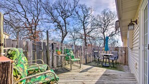 A wooden deck with outdoor furniture, including a chair and table, surrounded by a wooden fence.