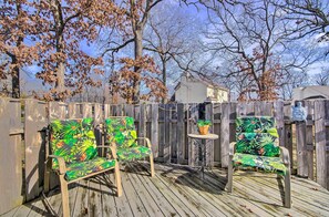 A wooden deck with two chairs and a small table, surrounded by a wooden fence and trees. - < Half-mi to Marinas: Osage Beach Home w/ Deck! (Osage Beach)