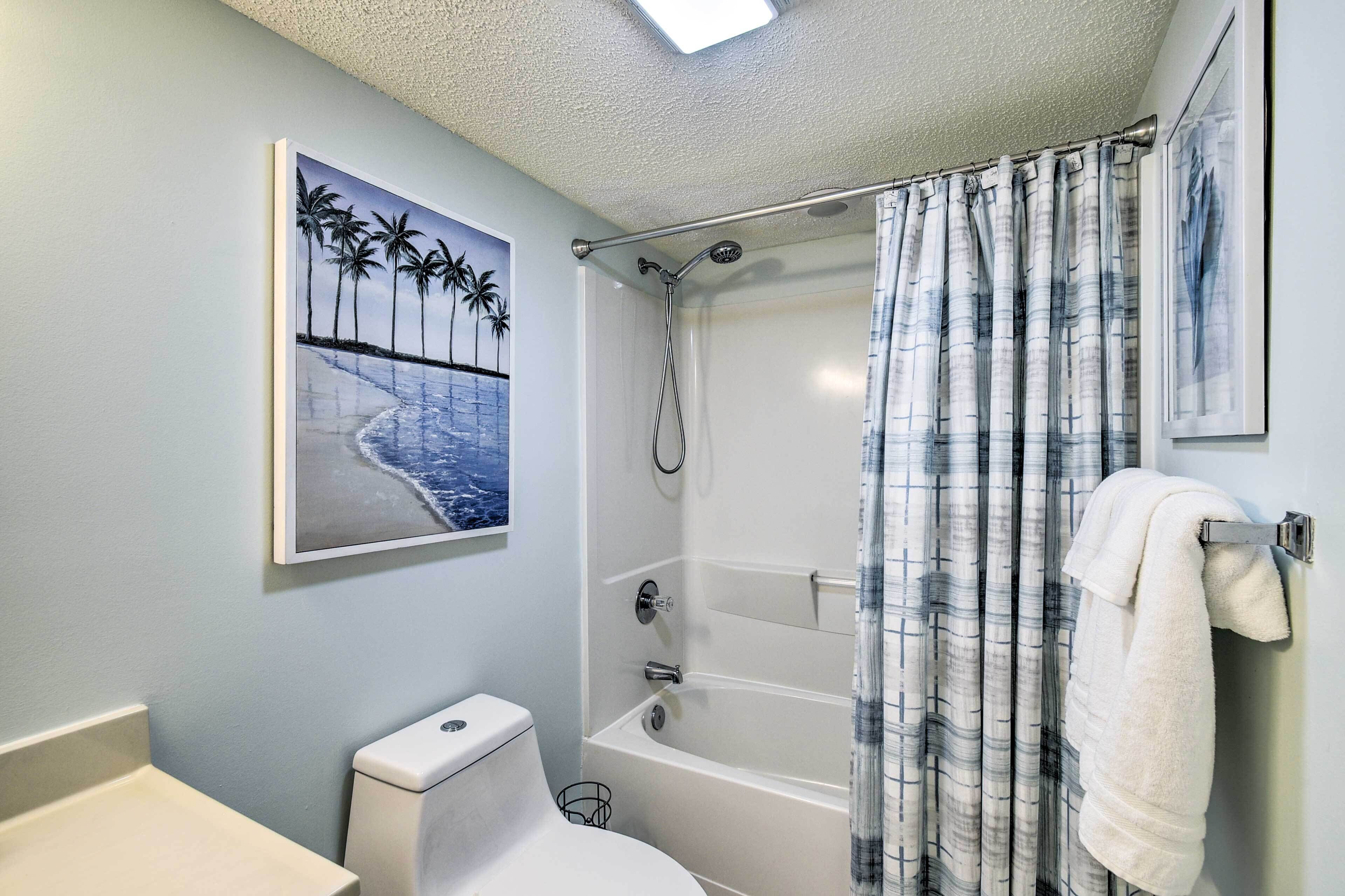 A bathroom with a bathtub, toilet, and a shower curtain.