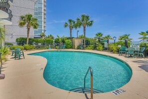 A swimming pool with a 3 FT depth marker, surrounded by palm trees and green chairs. - Oceanfront Condo w/ Balcony in Myrtle Beach! (Myrtle Beach)