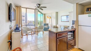 A compact hotel room with a kitchenette, a dining area with a table and chairs, a ceiling fan, and a large window offering a city view. - Walk to Shore: Condo w/ 2 Pools in Myrtle Beach (Myrtle Beach)