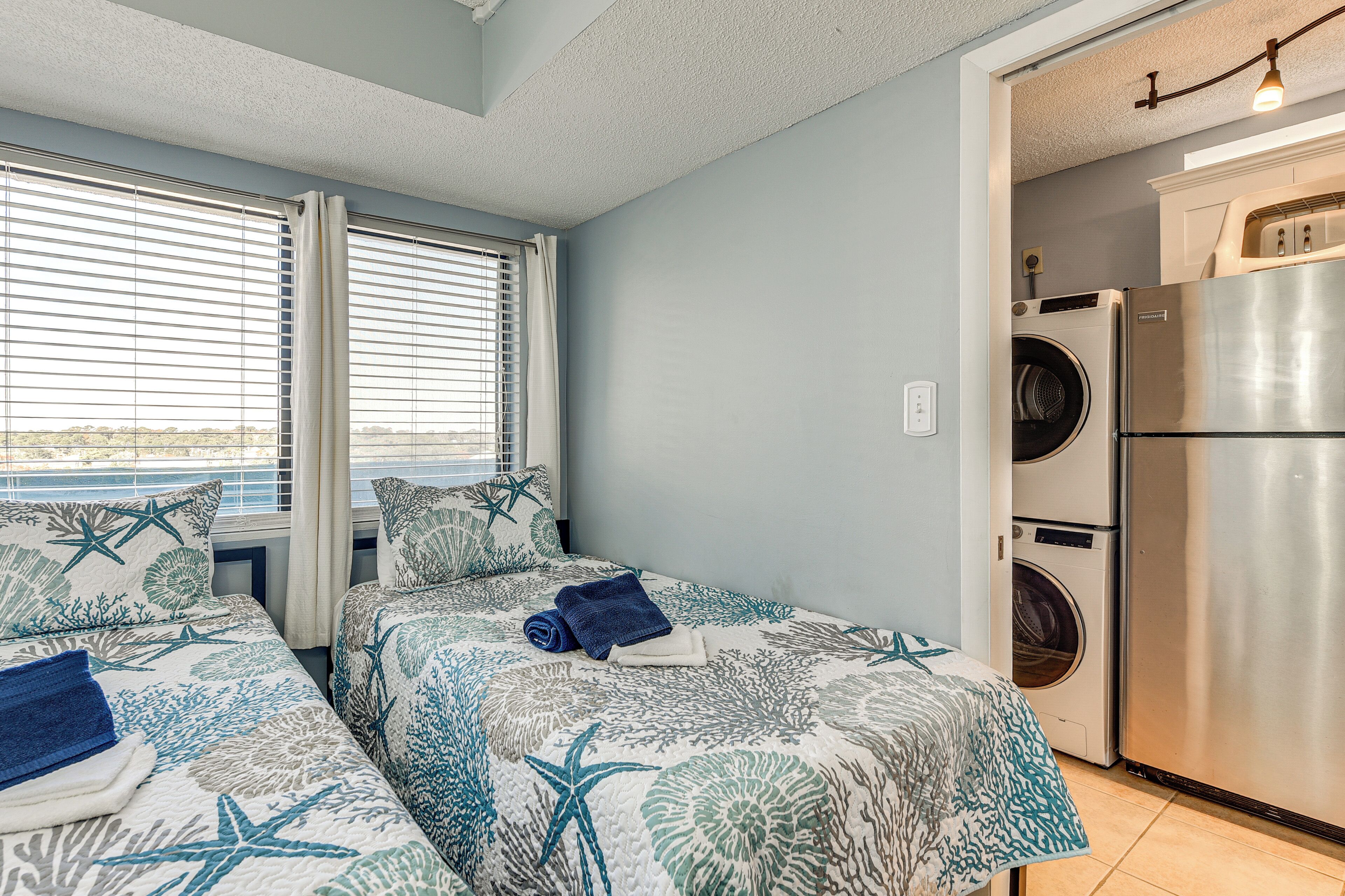 A room with two beds, a washing machine, and a refrigerator.