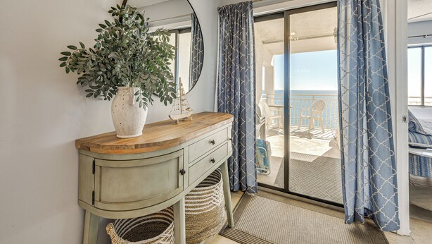 A room with a wooden vanity, a potted plant, a mirror, and a view of the balcony. - Ocean-view Penthouse Condo in North Myrtle Beach! (North Myrtle Beach)